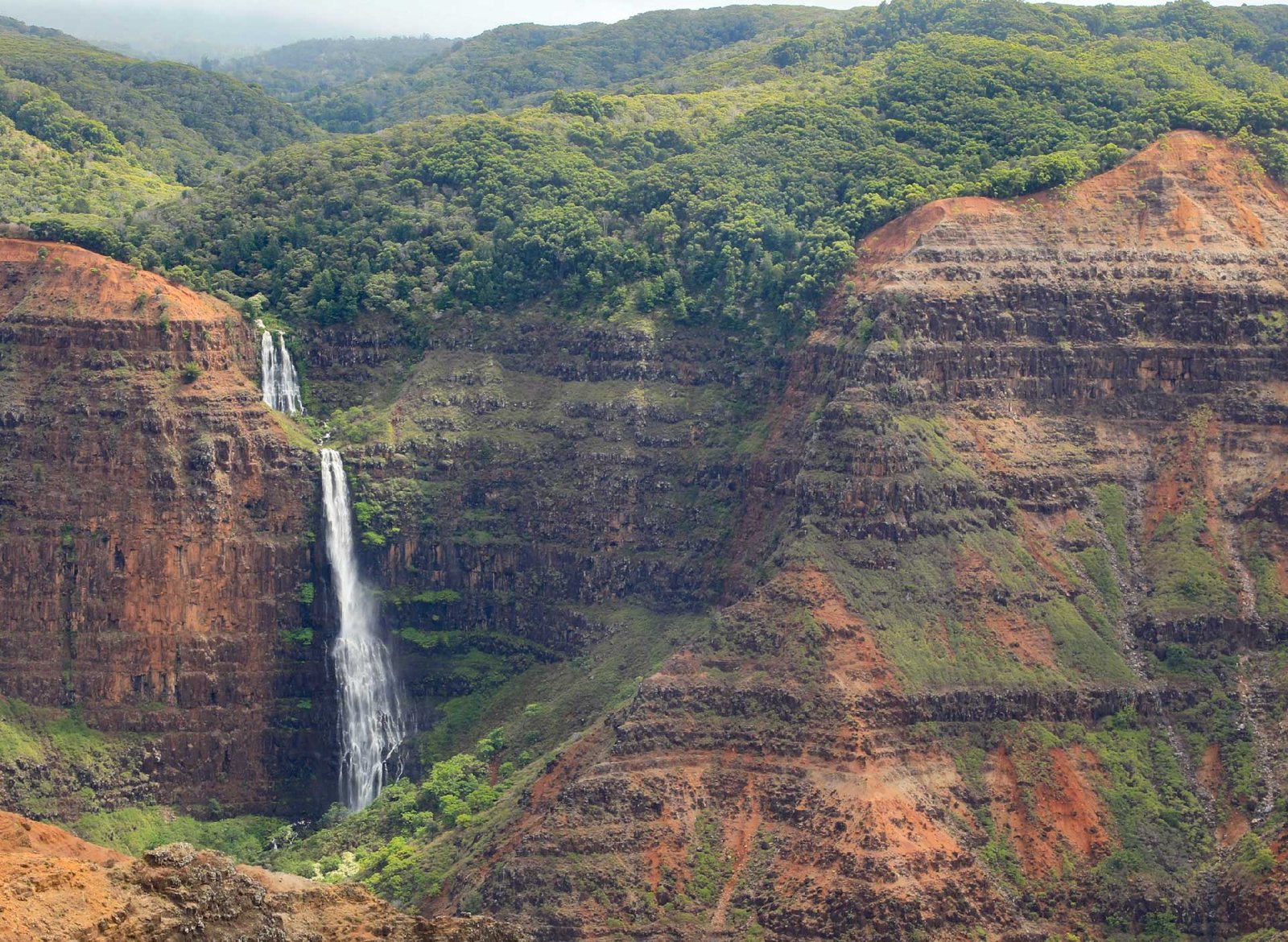 A waterfall pouring into Waimea Canyon, Kauaʻi